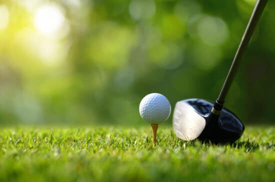 Tête de driver de golf à l'adresse derrière une balle sur tee, illustrant le choix du loft 9° ou 10,5°